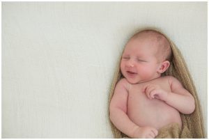 newborn baby smiling lying on blankets during newborn baby photography session