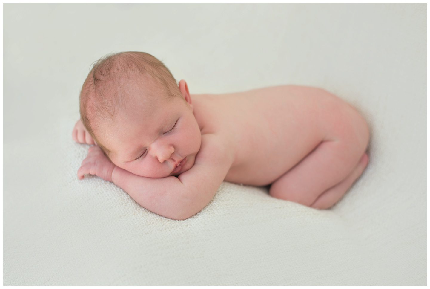 newborn baby girl laid on her tummy on a blanket during newborn photography session